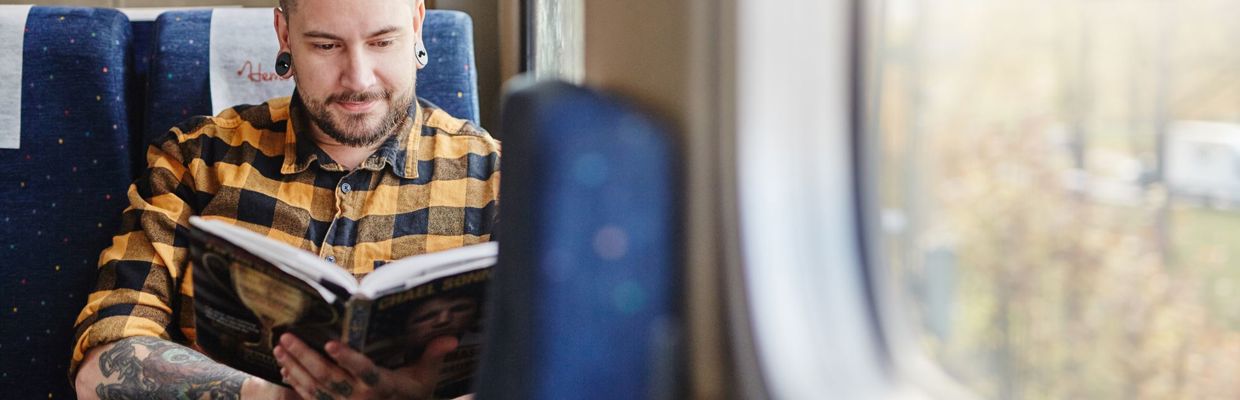 Resenär som läser bok på tåget.