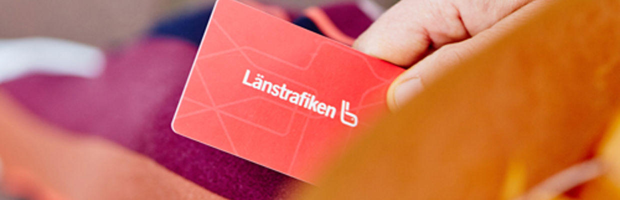 En närbild på ett rött resekort som en resenär håller i handen.