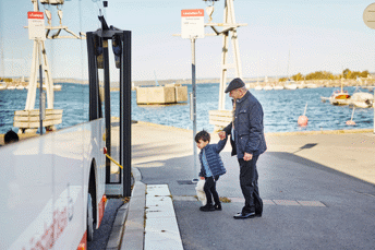 Äldre man som hjälper ett barn att gå ombord på bussen