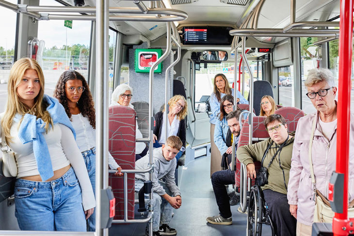 Resenärer som ger arga blickar mot en person längst bak i bussen
