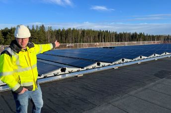 Man står på taket på tågdepån i Nässjö och visar solpanelerna