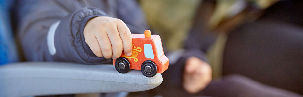 Bilden visar ett barn som leker med en leksaksbuss.