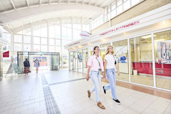 Bild på två resenärer som går förbi kundservicebutiken på Juneporten.