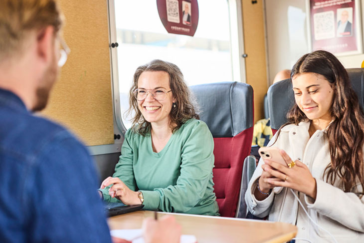 Bild på glada resenärer på ett tåg. 