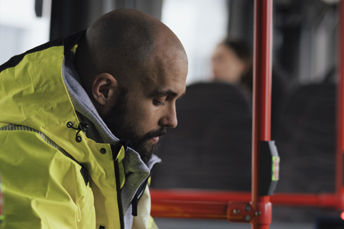 Resenär i varseljacka ombord på en buss. 