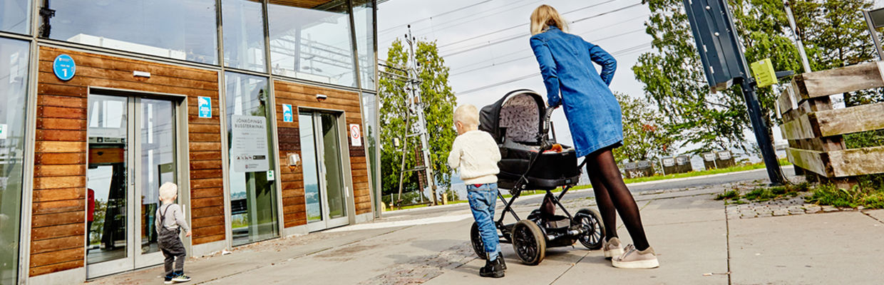 En kvinna går mot Jönköping resecentrum med en barnvagn. Bredvid sig har hon två små barn. 