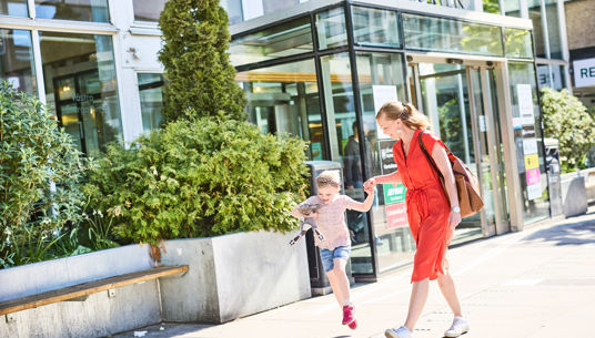 En bild på mor och dotter som går förbi Juneporten i Jönköping skrattandes hand i hand.