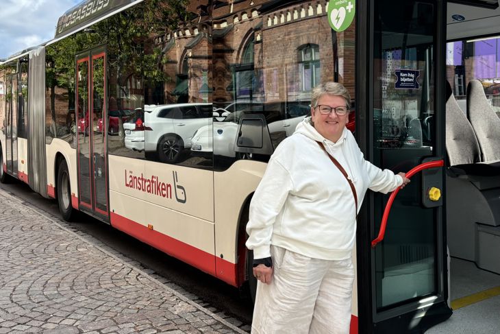Bild på vinnaren Karin Henriksson framför en av JLT:s bussar.